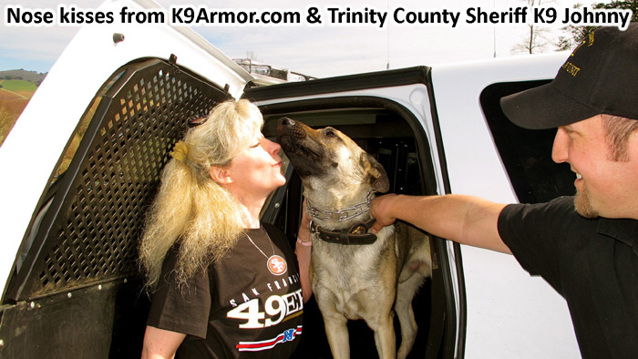 K9 Johnny gives k9 kisses to Suzanne Saunders for his K9 Armor vest. with smiles from Trinity County Sheriff's Deputy Nathaniel Trujillo